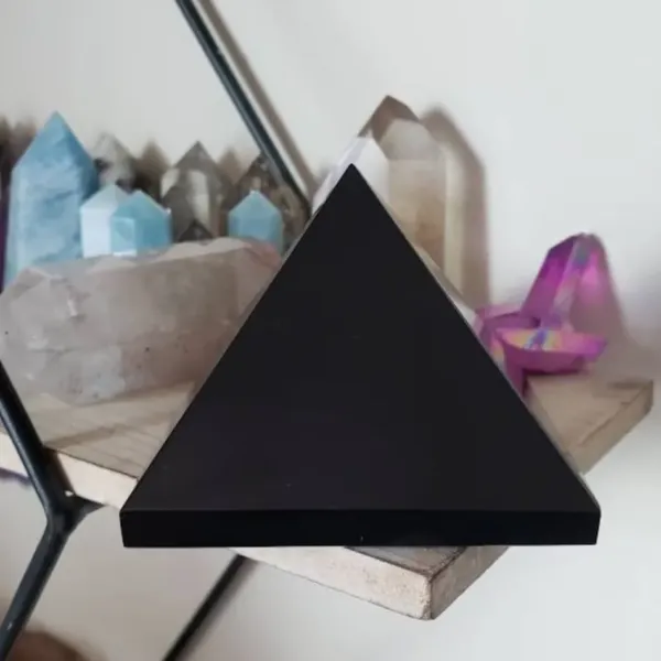 Black Onyx Pyramid on the shelf with different color crystals in the background