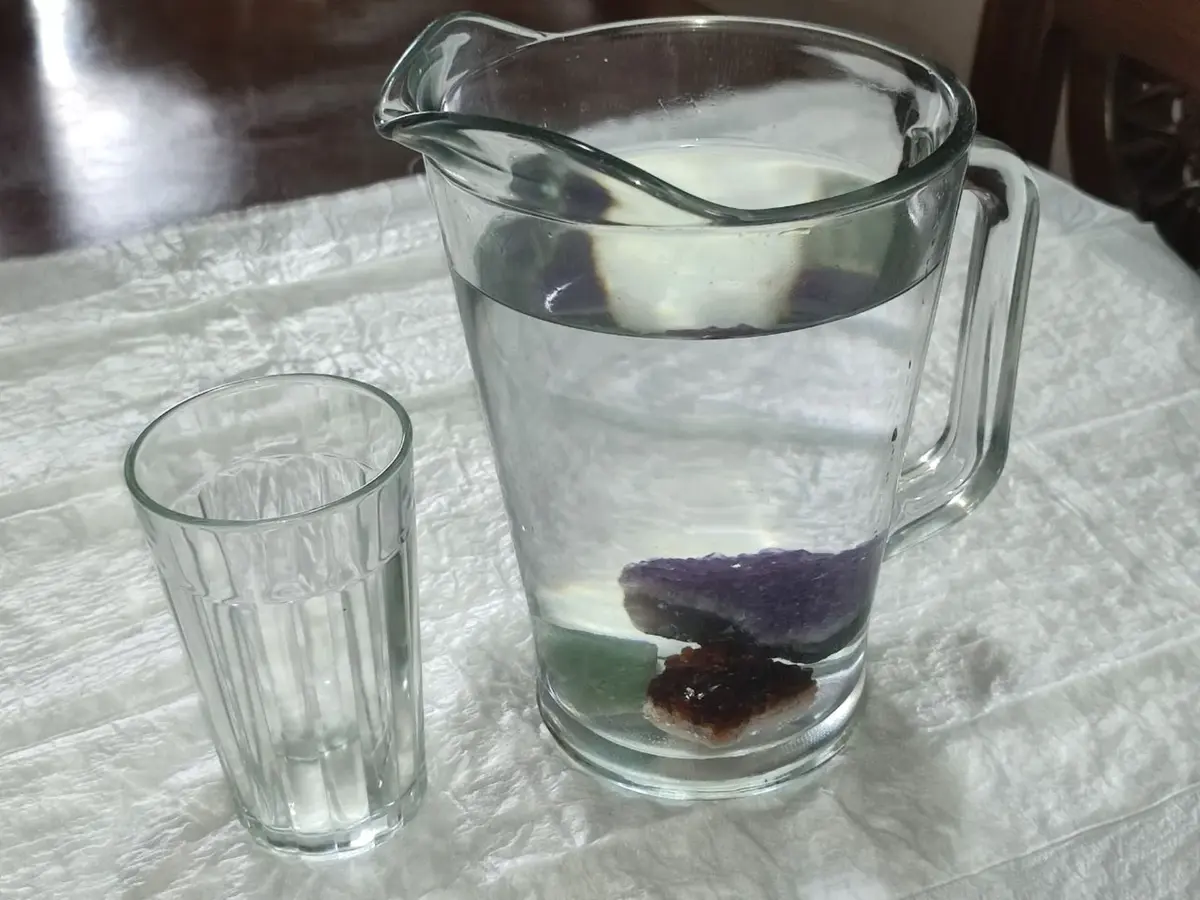 Amazonite, rose quartz, and amethyst in a pitcher of water - creating crystal elixir for holistic healing with crystals