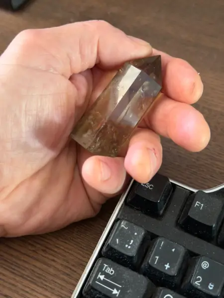 Hand holding citrine next to the keyboard - coming with ides to use crystals for gardening