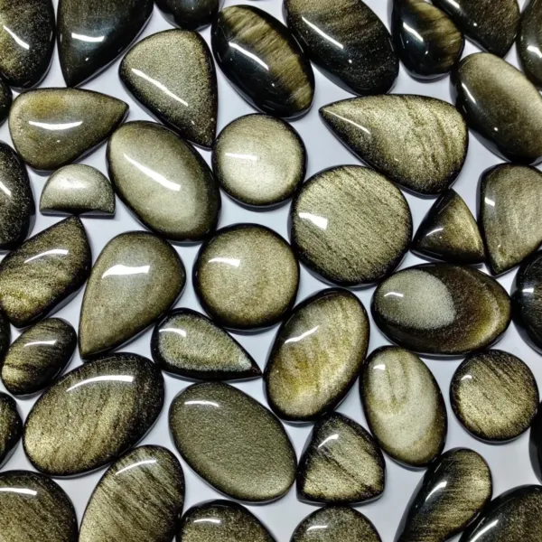 A group of Golden Sheen Obsidian Cabochons in different shapes - Oval, Pear, Round, Rectangle, Teardrop