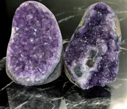 Two Natural Amethyst Cluster Geodes on black stone background