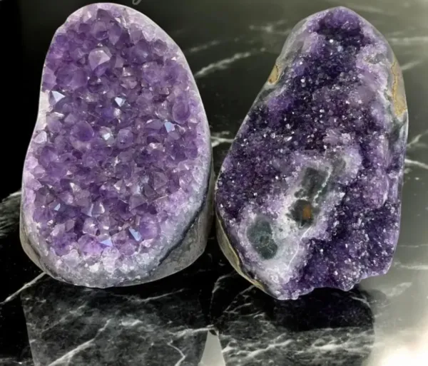 Two Natural Amethyst Cluster Geodes on black stone background