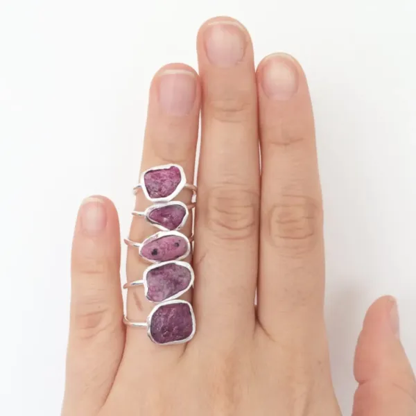 Five Raw Ruby silver Rings on the finger