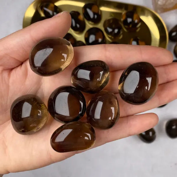 Seven pieces of Smoky Quartz Tumbled Stones on palm of the hand.