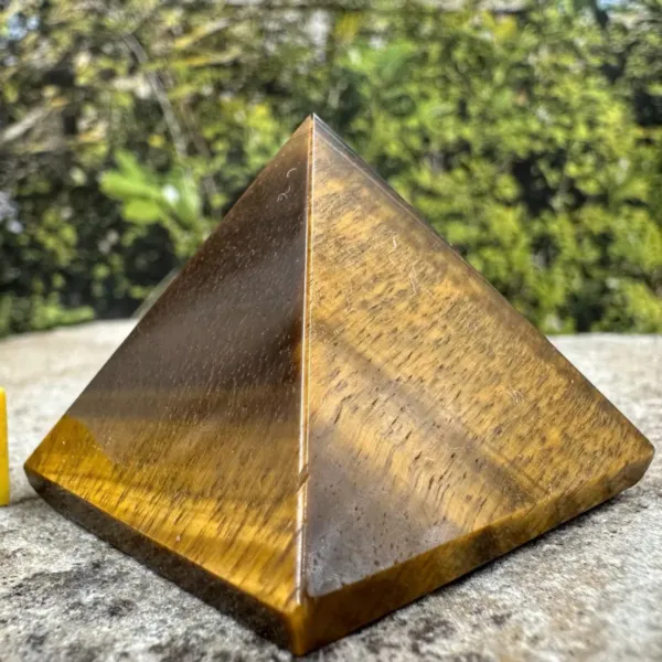 Tiger eye large pyramid placed on the top of the rock outdoors